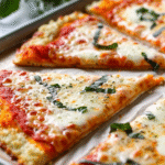 Slices of New York-style low-carb pizza topped with melted mozzarella, tomato sauce, and fresh basil.